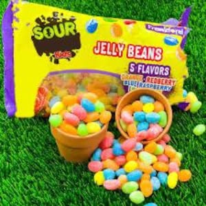 Può includere: Una confezione di jelly beans "Sour Kids" con 5 gusti, tra cui arancia, redberry, lampone blu. Due piccoli vasi di terracotta e jelly beans sparsi su erba verde.