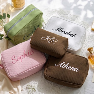Pu&ograve; includere: Cinque trousse per cosmetici personalizzate in vari colori: verde, bianco, rosa e marrone. Ogni trousse presenta nomi ricamati: Cecilia, Mirabel, Sophie, KR e Athena. Le trousse sono rettangolari con chiusura a cerniera.