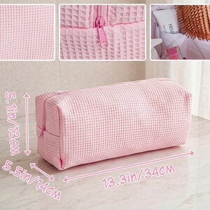 May include: A light pink rectangular toiletry bag with a waffle-textured fabric and a matching zipper closure. The bag measures 5.1 inches in height, 5.5 inches in depth, and 13.3 inches in length. The interior features white lining and pockets.