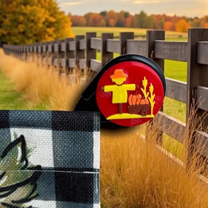 Może przedstawiać: Czerwono-czarny odświeżacz powietrza do samochodu z jesiennym motywem przedstawiającym stracha na wróble, dynie i pszenicę. Odświeżacz powietrza jest umieszczony na tle drewnianego płotu i jesiennych liści, z czarno-białą tkaniną w kratę na pierwszym planie.