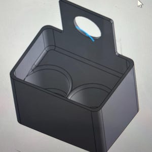 May include: A black, rectangular drink carrier with a handle and two circular compartments. The handle has a circular opening. The carrier is designed to hold two beverages.