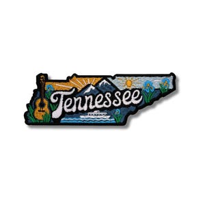 Può includere: Toppa ricamata a forma di Tennessee, con una chitarra, montagne e la scritta "Tennessee". La toppa ha un bordo nero e uno sfondo bianco. Il design include un'alba e fiori.