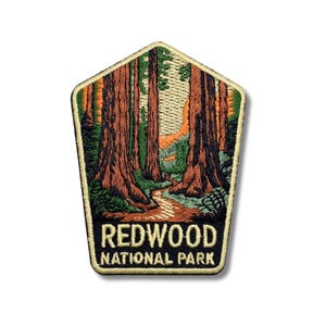 May include: Embroidered patch depicting a scene from Redwood National Park. The patch shows tall redwood trees in brown and green hues, with a path through the forest. The text "REDWOOD NATIONAL PARK" is at the bottom.
