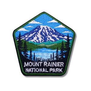 Puede incluir: Parche bordado con una vista del Parque Nacional Mount Rainier. El parche tiene forma de pentágono con un cielo azul, una montaña nevada, un lago y árboles de hoja perenne. El texto "MOUNT RAINIER NATIONAL PARK" está en la parte inferior.
