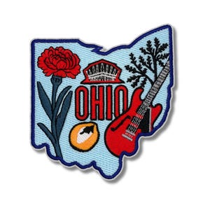 Puede incluir: Parche bordado con la forma de Ohio, con un clavel rojo, la palabra "OHIO" en rojo, una guitarra roja y otros símbolos estatales. El parche tiene un fondo azul claro con un borde azul oscuro.