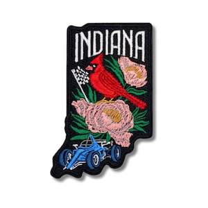 Könnte beinhalten: Gestickter Aufnäher in Form von Indiana mit einem roten Kardinal, rosa Blumen und einem blauen Rennwagen. Das Wort "INDIANA" ist in weißen Blockbuchstaben oben dargestellt. Der Aufnäher hat einen schwarzen Rand.