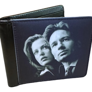 May include: Black bi-fold wallet featuring a black and white image of two people. The wallet is made of a dark material and has a smooth texture. The image on the front is a portrait.