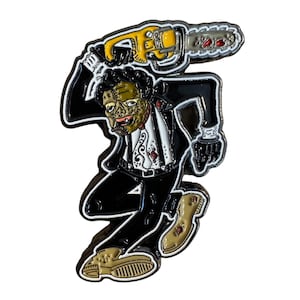 May include: Enamel pin featuring a zombie figure in a black suit, white shirt, and holding a yellow and silver chainsaw. The pin has a black outline and is on a white background.