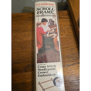 May include: A package for a scroll frame, with the text "F.A. Edmunds Scroll Frame". The package shows a woman and child working on a needlepoint project. The frame is designed for cross stitch, needlepoint, and crewel embroidery.