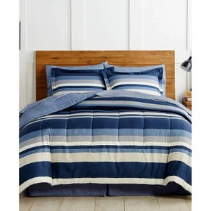 May include: A bedding set featuring a comforter and two matching pillow shams with a horizontal striped pattern in shades of navy blue, light blue, grey, and off-white. The comforter has a quilted texture and is paired with a solid navy bed skirt.
