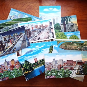 Puede incluir: Una colección de postales antiguas con vistas urbanas de Nueva Orleans, Luisiana. Las postales muestran varios estilos arquitectónicos, incluyendo edificios, calles y parques, con cielos azules y colores vibrantes. Algunas postales tienen texto.