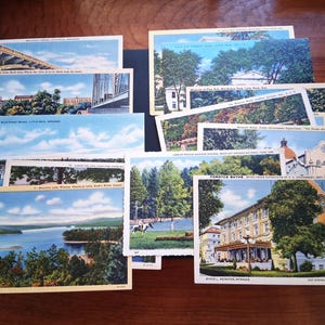 May include: A collection of vintage postcards featuring scenic views. The postcards depict bridges, lakes, buildings, and landscapes with blue skies and green trees. Some postcards have text, including place names like Little Rock, Arkansas.