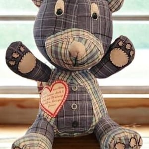 Op de afbeelding: Een handgemaakte teddybeer met een blauw, groen en beige geruit patroon. De beer heeft een hartvormige patch met tekst en knoopdetails. De poten en snuit van de beer zijn lichtbeige.