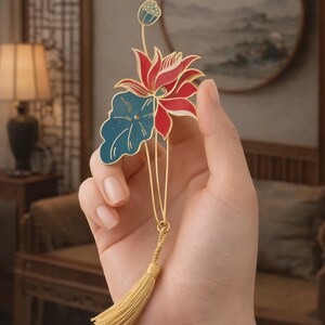 May include: A gold-colored lotus flower hairpin with red and blue enamel details and a gold tassel. The hairpin features a stylized lotus flower and leaf design, with a small bud at the top.