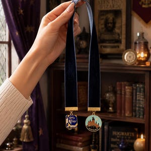 Könnte beinhalten: Zwei marineblaue Samtbuchzeichen mit goldfarbenen Anhängern. Ein Anhänger zeigt die Worte "Harry Potter" auf blauem Hintergrund. Der andere Anhänger zeigt Hogwarts Castle auf hellblauem Hintergrund. Die Lesezeichen werden vor einem Bücherregal gehalten.