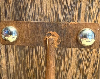 Op de afbeelding: Een houten oorbellen display met twee zilverkleurige, ronde oorstekers. De oorbellen zijn bevestigd aan een rechthoekige houten basis. De display staat tegen een houten achtergrond.
