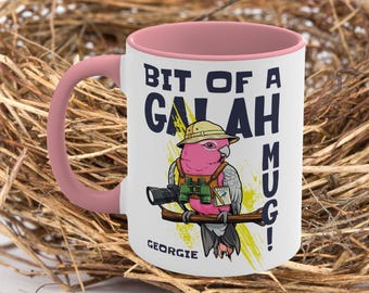 Puede incluir: Taza de cerámica blanca con interior y asa rosas. La taza presenta un dibujo de cacatúa galah de dibujos animados con sombrero de safari y prismáticos, con el texto "BIT OF A GALAH MUG!" y el nombre "GEORGIE".