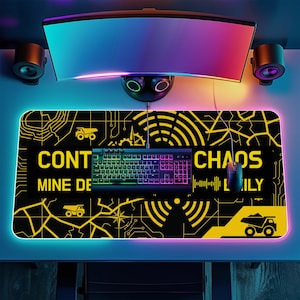 May include: A black and yellow gaming mousepad with the words "CONT CHAOS MINE DE LILY" and a circuit board design. A rainbow-lit keyboard and mouse sit on the pad. A curved monitor and speakers are above the pad.