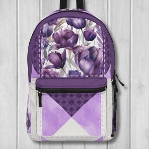 May include: Purple floral backpack with a watercolor tulip design. The backpack features a front zippered pocket, a side mesh pocket, and a padded back. The design includes a mix of purple, lavender, and white colors.