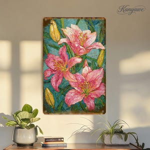 Puede incluir: Un letrero metálico rectangular con una pintura floral de lirios rosas y estambres amarillos sobre un fondo turquesa. El letrero tiene un aspecto envejecido y vintage, con la palabra "Kanyawae" en la esquina superior derecha.