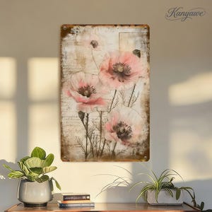 May include: A rectangular metal sign featuring a vintage floral design. The artwork showcases pink poppy flowers with dark centers against a backdrop of aged paper with script. The sign has a distressed, rustic appearance.
