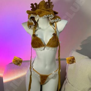 May include: A brown lingerie set with a reindeer antler hat, a triangle top, and a thong bottom. The set includes matching wrist cuffs. The lingerie is trimmed with white lace.