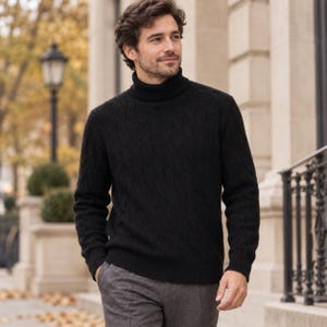 May include: A black long-sleeve turtleneck sweater featuring a subtle vertical wavy cable knit pattern. The garment has a ribbed collar, ribbed cuffs, and a ribbed hem, providing a textured appearance throughout the fabric of the sweater.