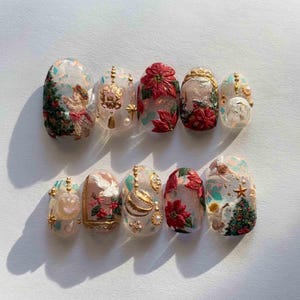 K&ouml;nnte beinhalten: Ein Set aus zehn k&uuml;nstlichen N&auml;geln mit Weihnachtsmotiv. Jeder Nagel zeigt aufwendige Designs, darunter Weihnachtsstern, Weihnachtsb&auml;ume und goldene Akzente. Die N&auml;gel sind in verschiedenen Farben lackiert, darunter Rot, Gr&uuml;n und Gold, mit einem gl&auml;nzenden Finish.