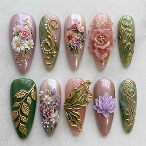 May include: A collection of ten almond-shaped artificial nails, each adorned with intricate floral and nature-inspired designs. The nails feature a variety of colors, including pink, green, and gold, with 3D embellishments of flowers, leaves, and swirls.