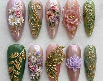 May include: A collection of ten almond-shaped artificial nails, each adorned with intricate floral and nature-inspired designs. The nails feature a variety of colors, including pink, green, and gold, with 3D embellishments of flowers, leaves, and swirls.