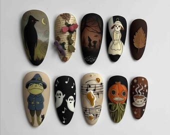 May include: A set of ten almond-shaped false nails with various Halloween-themed designs. The designs include a black crow, a forest scene, a scarecrow, a frog, ghosts, musical notes, a jack-o'-lantern, and a cup of coffee.