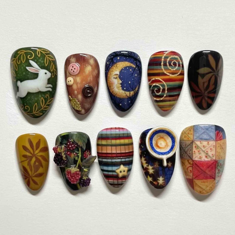 Pu&ograve; includere: Una collezione di dieci unghie finte con design unici. Ogni unghia presenta opere d'arte intricate, tra cui un coniglio bianco, bottoni, una luna crescente e vari motivi. Le unghie ovali variano per colore e design.