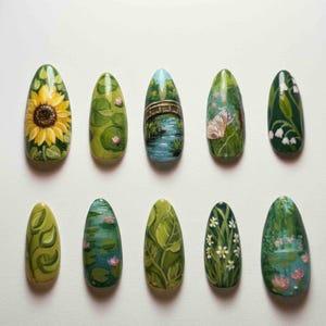 May include: A collection of ten painted nail art designs. Each nail features a different nature-inspired scene, including a sunflower, lily pads, a bridge over water, a butterfly, and various floral and leaf patterns. The nails are oval-shaped and painted on a white surface.