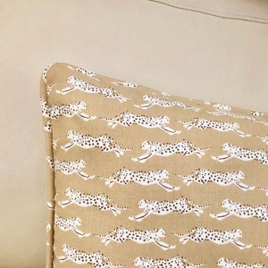May include: A tan pillow with a white cheetah print pattern.