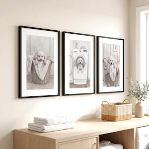 May include: Three framed wall art prints featuring a light-colored dog. The left and right prints show the dog in a wicker basket with a blanket. The center print shows the dog inside a white washing machine. All frames are black with white mats.