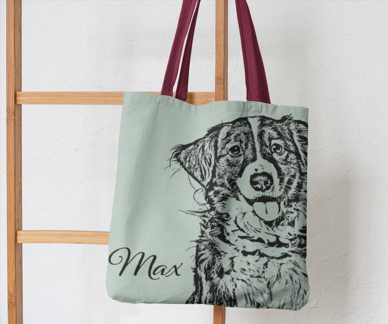 Puede incluir: Una bolsa de lona verde claro con una ilustraci&oacute;n en blanco y negro de la cabeza de un perro. El perro est&aacute; mirando a la c&aacute;mara con la lengua fuera. El nombre "Max" est&aacute; impreso en negro en la bolsa.