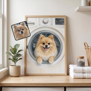 May include: A framed wall art print featuring a light brown Pomeranian dog peeking out from the circular door of a white washing machine. A smaller, square-shaped inset image of the same dog is positioned to the left of the main illustration.