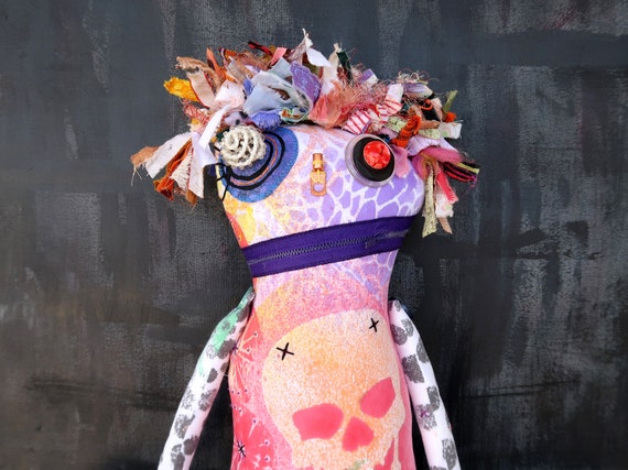 A large one-of-a-kind handcrafted textile art doll that sits in the uncanny valley of creepy-cute — no two are alike and someone's hands made every stitch.