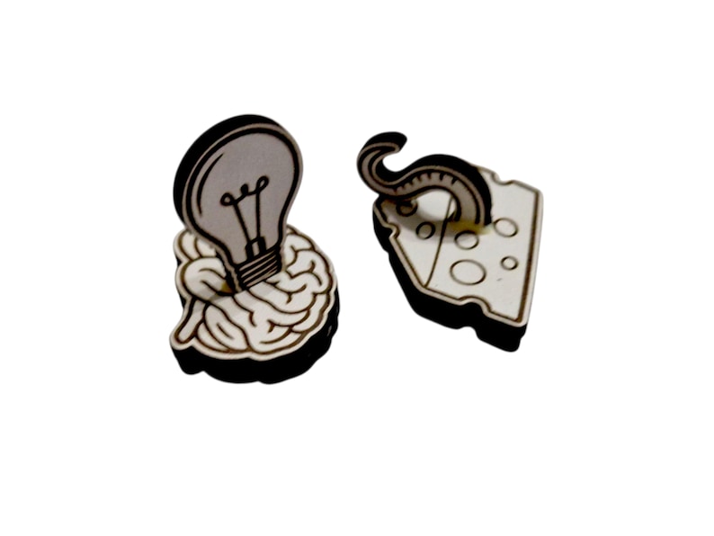 May include: Wooden earrings featuring a lightbulb over a brain and a tentacle over a cheese wedge. The earrings have a black outline and are made of light-colored wood. The lightbulb is gray with a black filament.