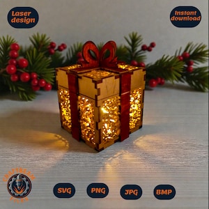 Könnte beinhalten: Eine lasergeschnittene Holzgeschenkbox mit rotem Band und Schleife. Die Box hat aufwendige Ausschnitte und ist von innen beleuchtet. Die Wörter "Laser design" und "Instant download" sind sichtbar. Umgeben von Grün und roten Beeren.