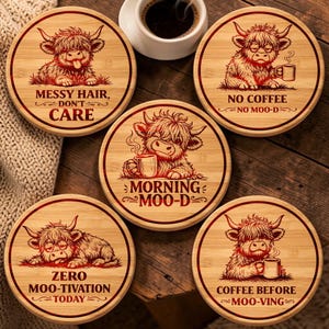May include: Five round bamboo coasters featuring illustrations of Highland cattle. Each coaster displays a unique cow graphic and text: Messy Hair, Don't Care; No Coffee No Moo-d; Morning Moo-d; Zero Moo-tivation Today; and Coffee Before Moo-ving.