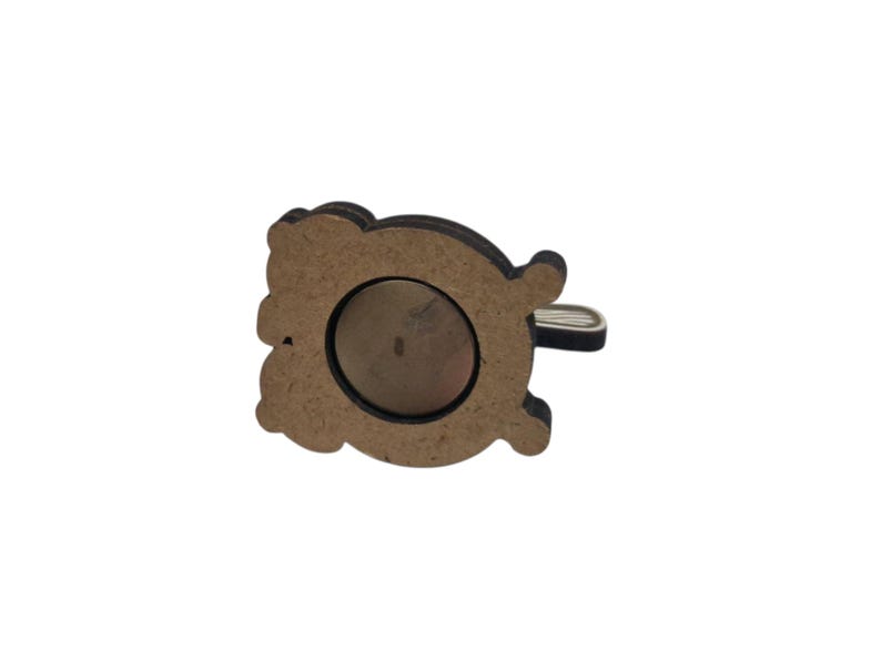 May include: A wooden magnet with a decorative bear shape. The bear is brown with a dark brown outline and a silver-colored metal loop. A circular magnet is visible on the back.