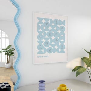 May include: A framed poster with a light blue geometric design and icons, with the words "GRAB & GO" at the bottom. The poster is hanging on a white wall in a room with a modern aesthetic. A plant and a table are in the foreground.