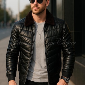 Puede incluir: Chaqueta de cuero negra con diseño acolchado, cuello de piel marrón y cierre de cremallera. La chaqueta se lleva sobre una camiseta gris y combinada con pantalones negros. Un reloj y gafas de sol completan el look. El texto "Pearls at Ham Corner" es visible.