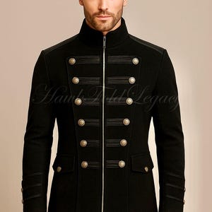 May include: Black military-style jacket with a high collar, gold buttons, and a zip closure. The jacket features decorative bands across the chest and on the sleeves. The text "Hawk Field Legacy" is visible on the jacket.