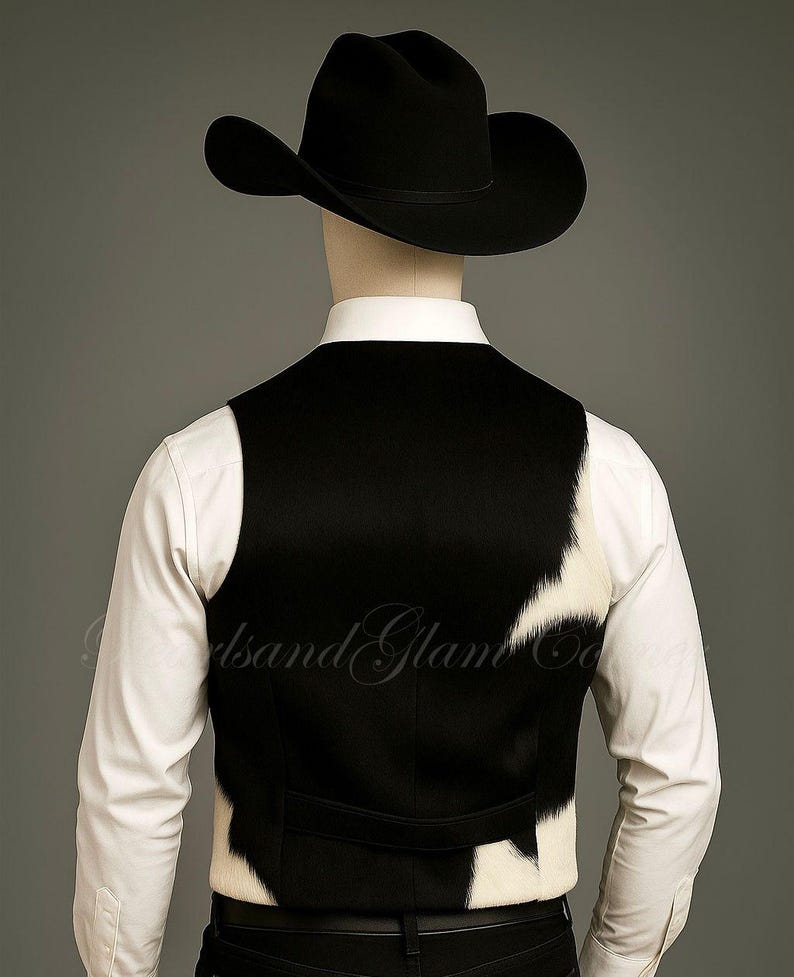 May include: A black cowboy hat worn with a white long-sleeved button-down shirt and a vest featuring a black and white cowhide pattern. The vest has a solid black back panel and a horizontal strap across the lower back area, worn over dark trousers.