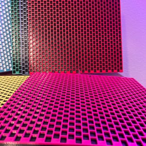 May include: A collection of square, flat panels featuring a grid of small, hollow rectangular cutouts. The panels are displayed in various vibrant colors including red, pink, yellow, green, blue, and black, arranged in a stacked, overlapping formation.