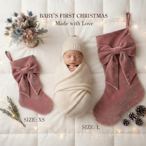 Può includere: Un neonato avvolto in una fascia e un berretto in maglia color crema, affiancato da due calze natalizie in velluto rosa polvere con grandi fiocchi. Il testo recita BABY'S FIRST CHRISTMAS, Made with Love, SIZE: XS e SIZE: L.