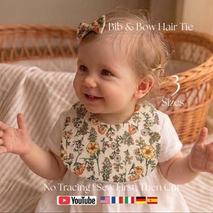 May include: A baby wearing a floral bib and a matching bow hair tie. The bib has a cream background with a pattern of yellow and orange flowers and green leaves. Text on the image reads "Bib & Bow Hair Tie" and "3 Sizes".