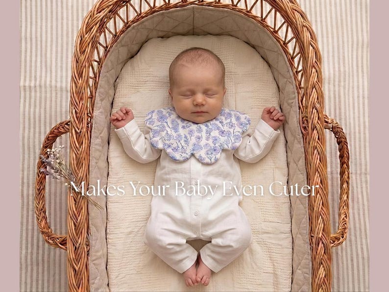 May include: A sleeping baby wearing a white onesie and a blue floral bib, lying in a wicker bassinet. The text "Makes Your Baby Even Cuter" is visible in the image.